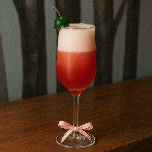 Cóctel primaveral rosado con cereza y limón en copa de hechizo